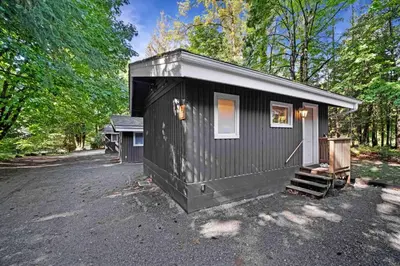 a black tiny house sitting in the woods at Sunwolf Riverside Cabins in Brackendale