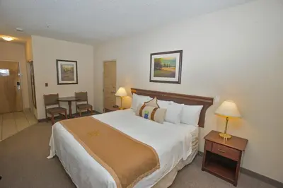 a hotel room with a large bed and a table at Lakeview Inns & Suites - Chetwynd in Chetwynd