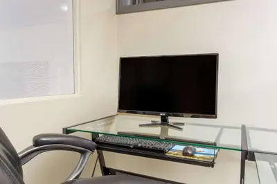 a glass desk with a computer monitor and a keyboard at Ramada by Wyndham Williams Lake in Williams Lake