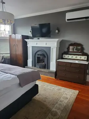 a bedroom with a fireplace and a bed and a television at The Ivy on Parker Guest House in Vancouver