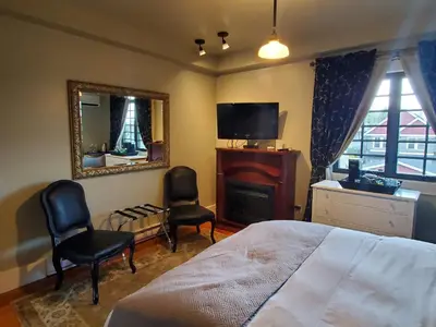 a bedroom with a bed and two chairs and a mirror at The Ivy on Parker Guest House in Vancouver