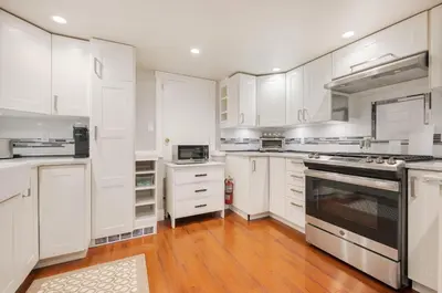 a large white kitchen with white cabinets and appliances at The Ivy on Parker Guest House in Vancouver