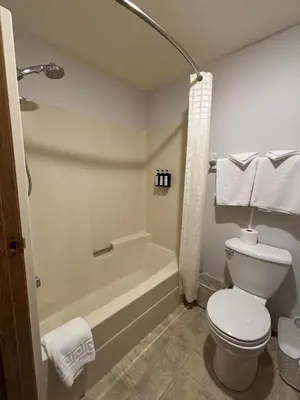 a bathroom with a toilet and a shower with towels at Western Traveller Motel in Grand Forks