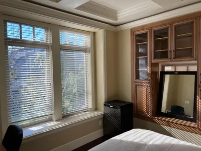 a bedroom with a bed and two windows with a television at Mike's Luxury House in Vancouver