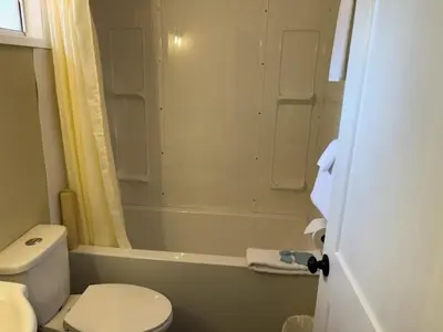a bathroom with a toilet and a tub and a shower at Pioneer Inn by the River in Port Hardy