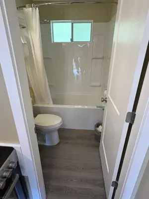 a bathroom with a toilet and a tub and a window at Pioneer Inn by the River in Port Hardy