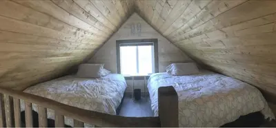 two beds in a wooden room with a window at Cougar Mountain Lodge and Resort Cabin Rentals in Valemount