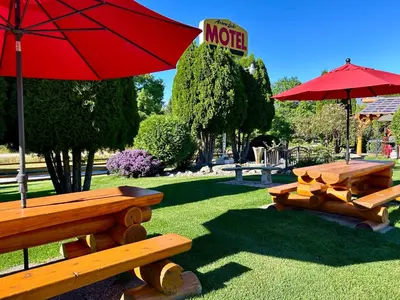 two picnic tables and a red umbrella in a park at Arrow Lake Motel in Fauquier