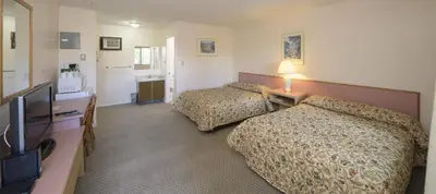 a hotel room with two beds and a flat screen tv at Beachside Motel in Penticton