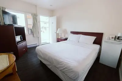 a bedroom with a large white bed and a window at Beachside Motel in Penticton