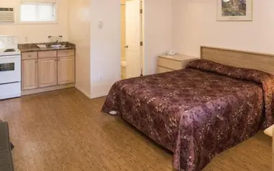 a hotel room with a bed and a kitchen at Beachside Motel in Penticton