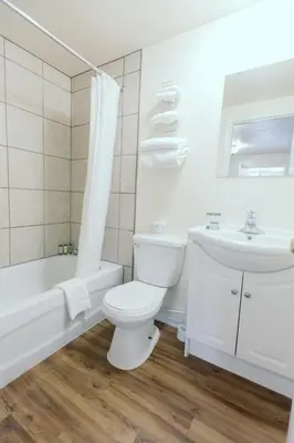 a white bathroom with a toilet and a sink at Beachside Motel in Penticton