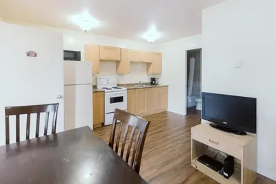 a kitchen with a dining room table and a television at Beachside Motel in Penticton