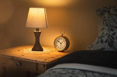 a bedside table with a lamp and a clock on it at Willow Grove B&B Inn in Horsefly