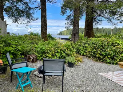 two chairs and a table in a yard with trees at So Damn Lucky Glamping in Ucluelet