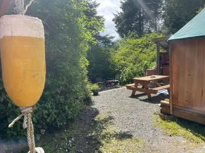 a drink container attached to a bush next to a picnic table at So Damn Lucky Glamping in Ucluelet