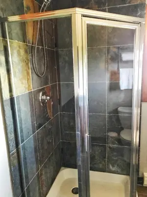 a shower with a glass door in a bathroom at Wesbert Winery & Guest Suites in Penticton