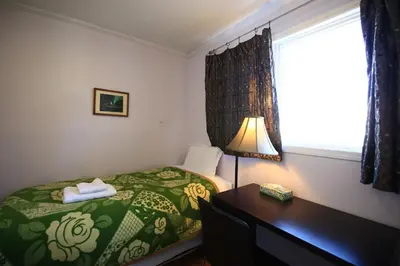 a bedroom with a bed and a desk and a window at Jenny Guest House in Yellowknife