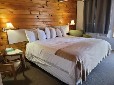 a bedroom with a large bed with a wooden wall at Pines Motel in Sicamous