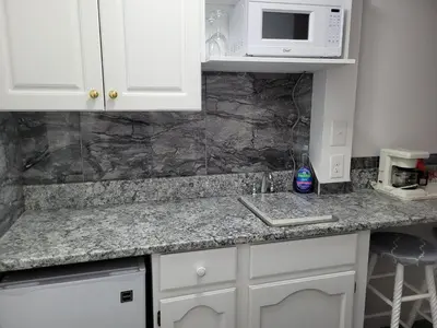 a kitchen counter with a microwave and a sink at Pines Motel in Sicamous