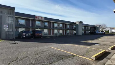 a hotel with cars parked in a parking lot at Prince Motel in Prince George