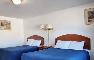 two beds in a hotel room with blue sheets at Prince Motel in Prince George