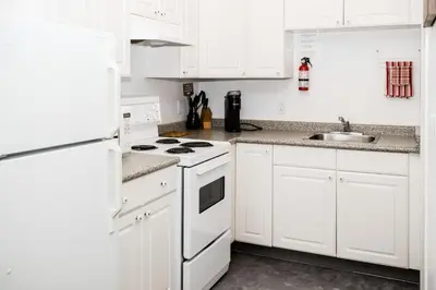 a white kitchen with white cabinets and a sink at Crescent Motel in Radium Hot Springs