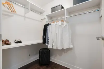 a walk in closet with white clothes and a suitcase at Level Vancouver Yaletown - Seymour in Vancouver