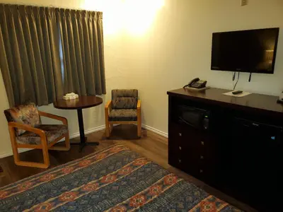 a hotel room with a bed and a tv and a table at Battlefords Inn in North Battleford
