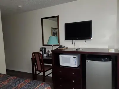 a hotel room with a desk with a microwave and a television at Battlefords Inn in North Battleford