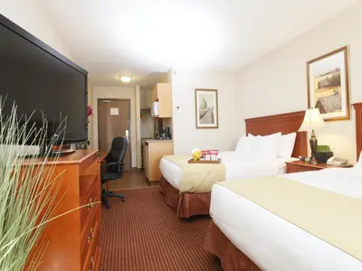 a hotel room with two beds and a flat screen tv at Stonebridge Hotel Dawson Creek in Dawson Creek