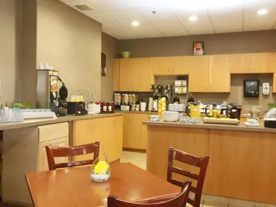 a kitchen with a table and chairs and a counter at Stonebridge Hotel Dawson Creek in Dawson Creek