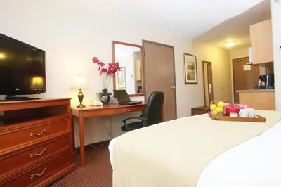 a hotel room with a bed and a desk with a television at Stonebridge Hotel Dawson Creek in Dawson Creek