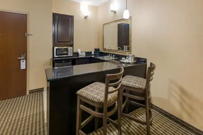 a hotel room with a kitchen with a sink and two chairs at Best Western Sunrise Inn & Suites in Stony Plain