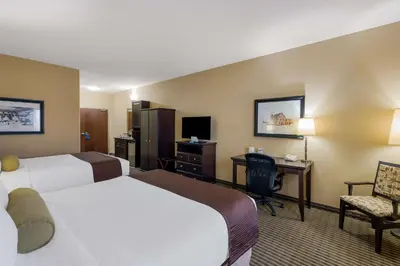 a hotel room with two beds and a desk at Best Western Sunrise Inn & Suites in Stony Plain