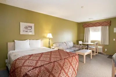 a hotel room with a bed and a chair at Bow River Inn in Cochrane