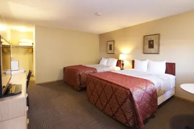 a hotel room with two beds and a television at Bow River Inn in Cochrane