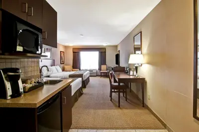 a hotel room with a kitchen and a bedroom at Canalta Oyen in Oyen