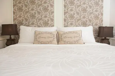 a white bed with two pillows on it with two lamps at The Craigmyle Inn in Victoria