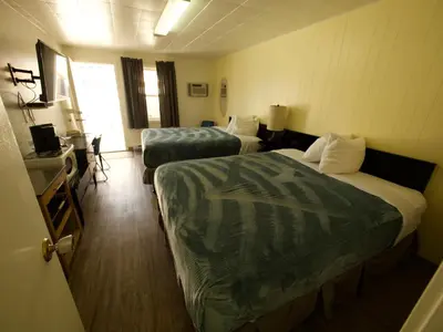 a hotel room with two beds and a table at Creston Valley Motel in Creston