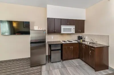 a kitchen with a stainless steel refrigerator and wooden cabinets at Comfort Inn in Dawson Creek