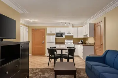 a living room with a blue couch and a kitchen at Nova Inn Yellowknife in Yellowknife