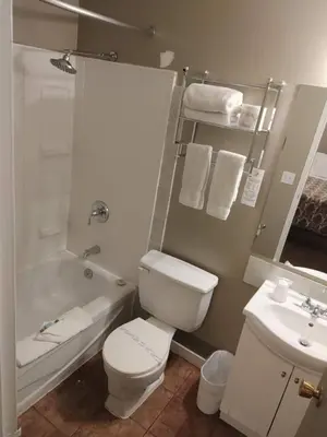 a bathroom with a toilet and a tub and a sink at Magnuson Hotel Creston in Creston