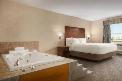 a hotel room with a bed and a bath tub at Days Inn & Suites by Wyndham Brooks in Brooks