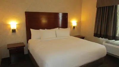 a bedroom with a large bed with white sheets and pillows at Days Inn & Suites by Wyndham Brooks in Brooks
