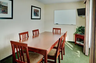 a dining room table with chairs and a white board at Lakeview Inns & Suites - Slave Lake in Slave Lake