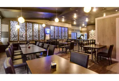 a dining room with tables and chairs and windows at Motel 6 Kerrobert, SK in Kerrobert