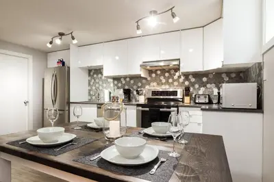 a kitchen with a table with plates and wine glasses at Modern Executive Suite I Complimentary Netflix & Parking! in Edmonton
