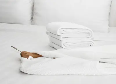 a white bed with a pile of towels on it at Pomeroy Hotel Fort St. John in Fort Saint John