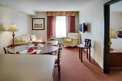 a hotel room with a table and a living room at Pomeroy Inn and Suites Chetwynd in Chetwynd